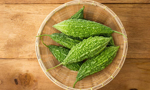 Top view of green bitter gourds in the basket on wood background.